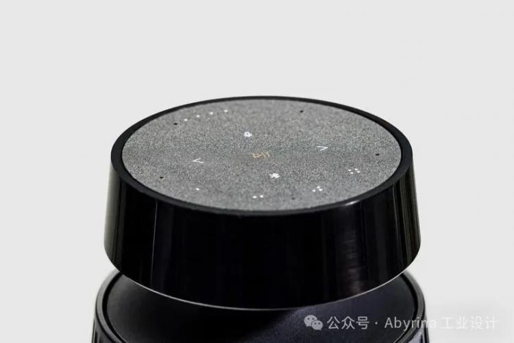 A close-up view of a black Bang & Olufsen smart speaker with a touch-sensitive surface displaying white icons and a power symbol in the center.