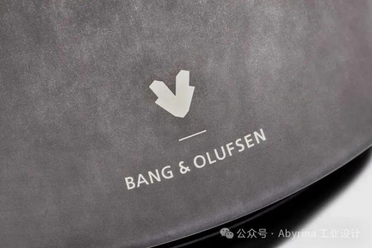 Close-up of the Bang & Olufsen logo printed in white on a matte gray surface, showcasing the brand's signature minimalist elegance.