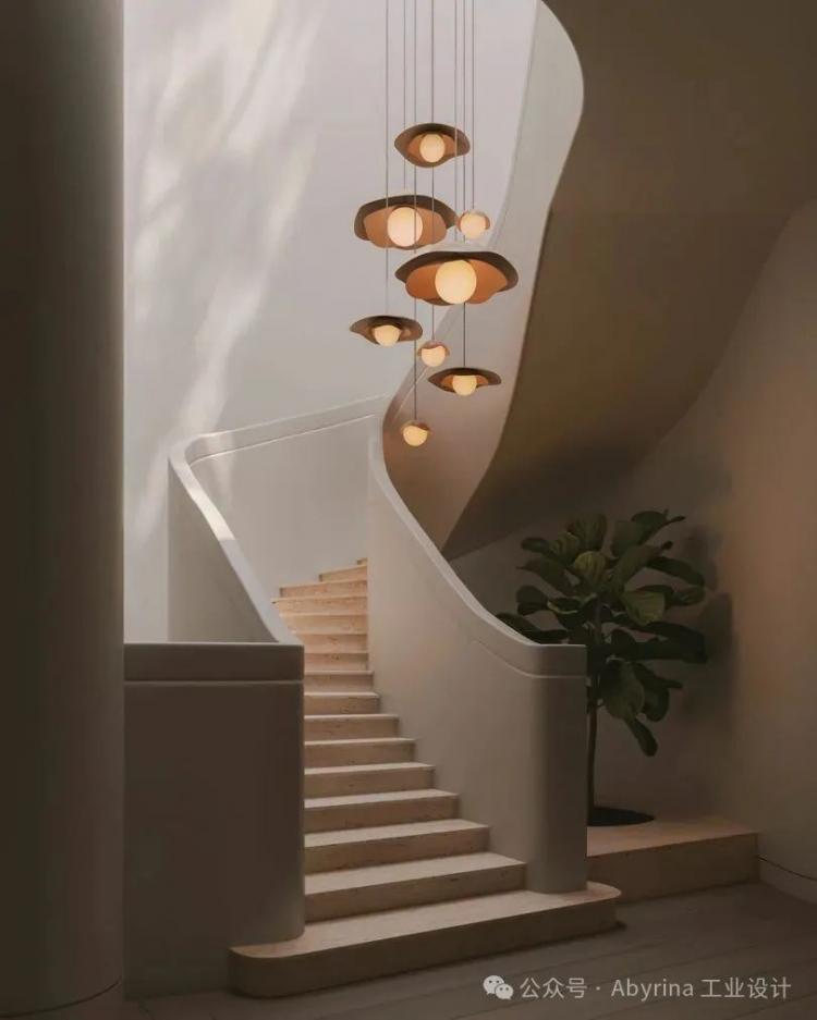 Curved staircase with beige steps, white walls, modern pendant lights, and a potted plant on the landing in a minimalist interior.