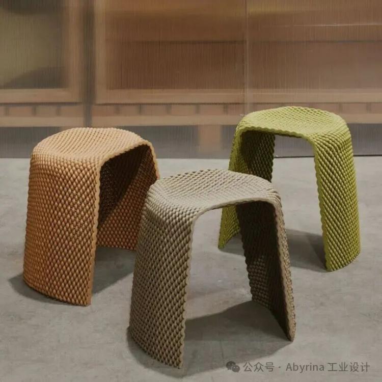 Three textured stools in orange, green, and beige colors sit on a concrete floor