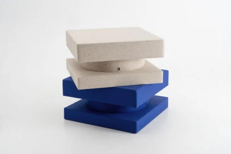 Three square cushions, two beige and one blue, are stacked in an alternating pattern against a plain white background.