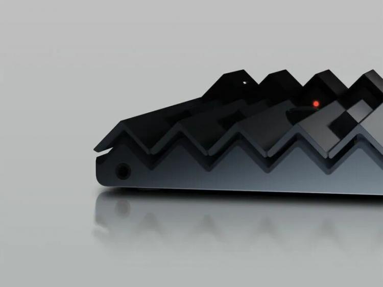 Close-up of a black, zigzag-patterned electronic device with a small red indicator light, placed on a reflective surface.