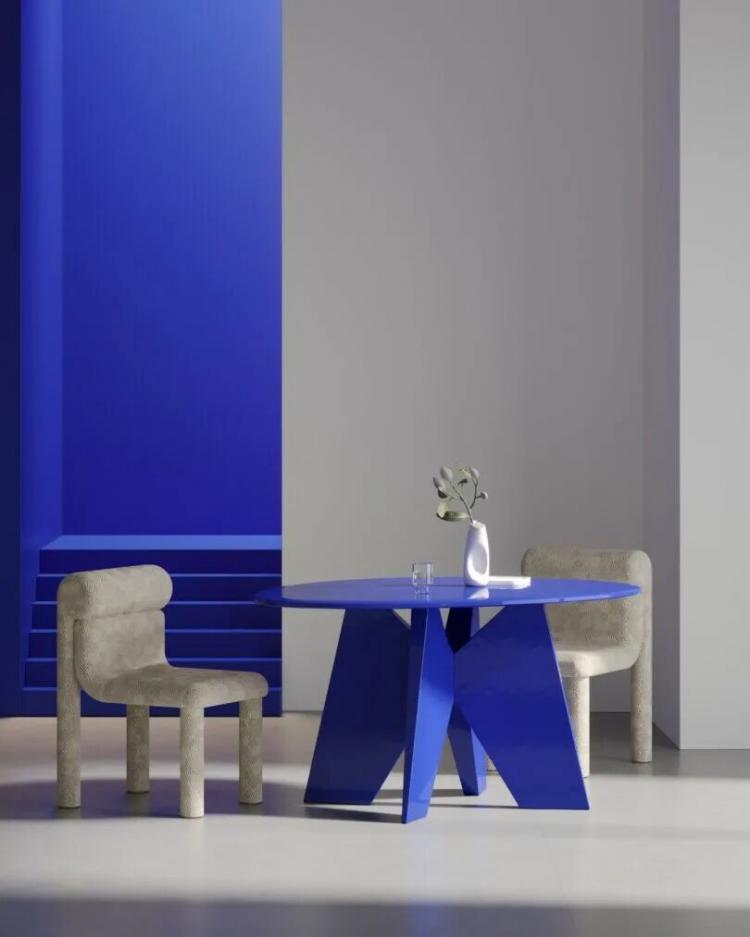 A modern room with a round blue table, two beige chairs, a white vase with flowers, and a glass cup, set against a blue and gray geometric background