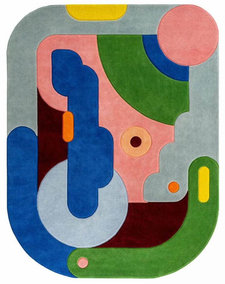 Abstract rug with rounded edges designed by Sam Buckley, featuring colorful geometric shapes in blue, green, pink, yellow, orange, gray, and burgundy on a textured surface.