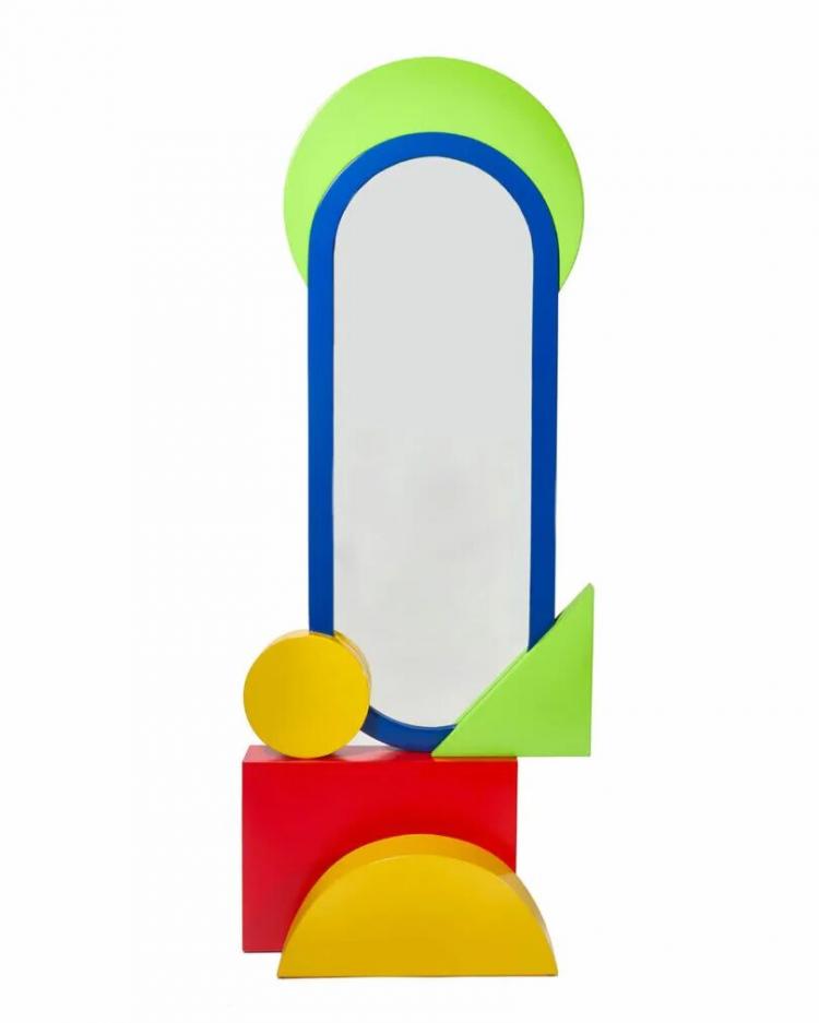 A tall, oval mirror with a blue frame, accented by green, yellow, and red geometric shapes including circles, squares, and triangles.